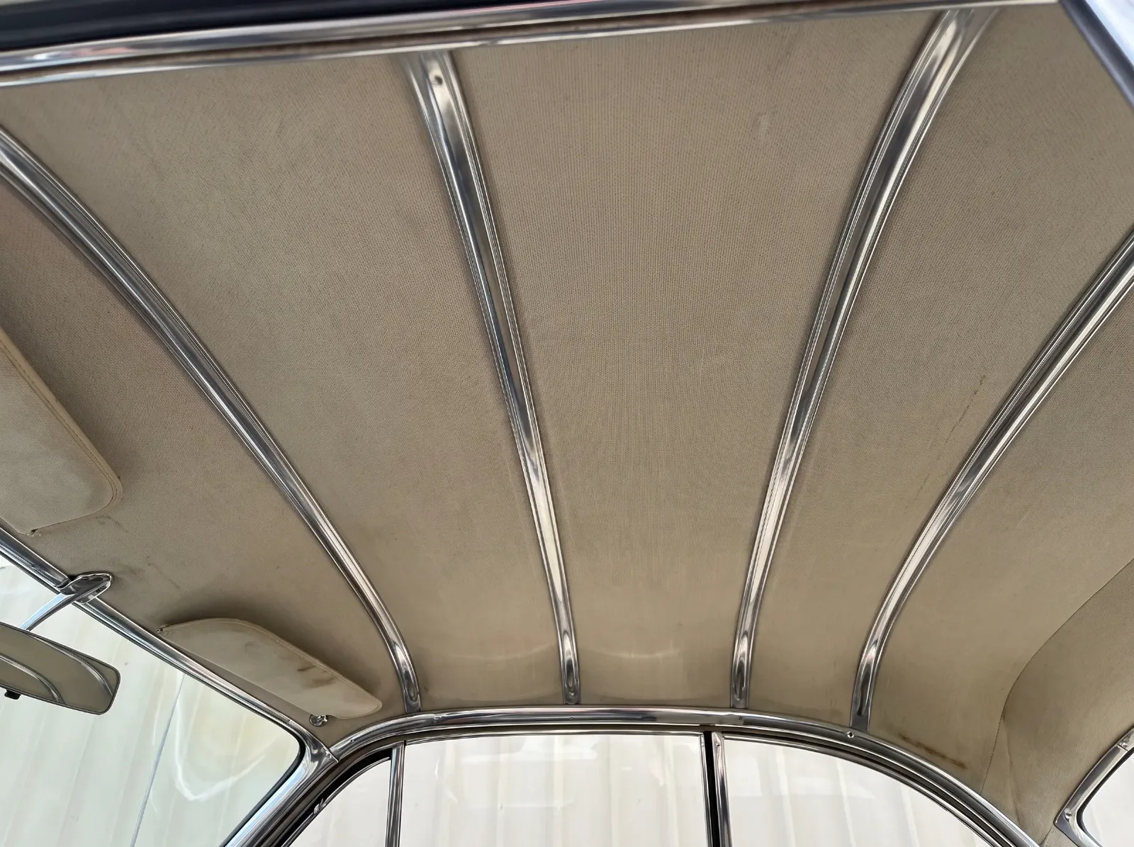 Chrome crossbars running across the headliner of an early 1950s hardtop in the pattern of convertible top bows
