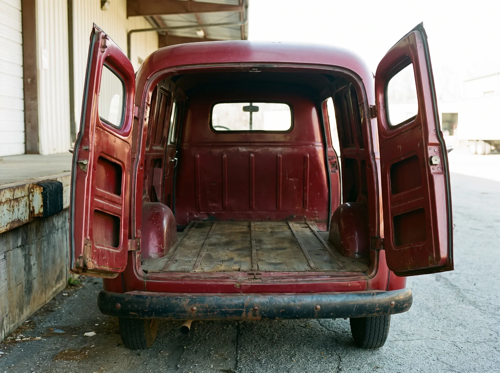 Panel truck with both rear doors swung open, showing the wooden load floor and bare metal walls