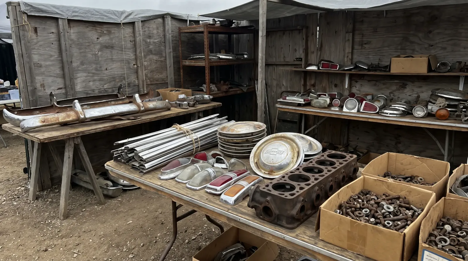 Swap meet tables loaded with early 1950s Chevrolet parts, bumpers, trim strips and hubcaps