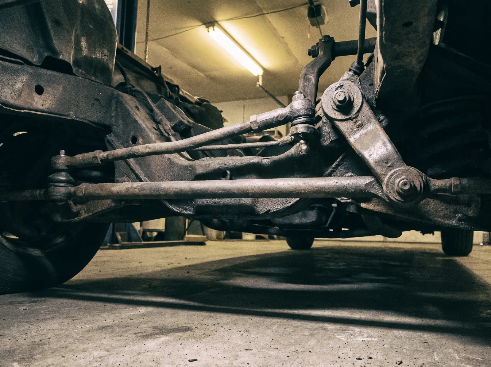 Idler arm and centre link under the front of an early 1950s Chevrolet, seen from below