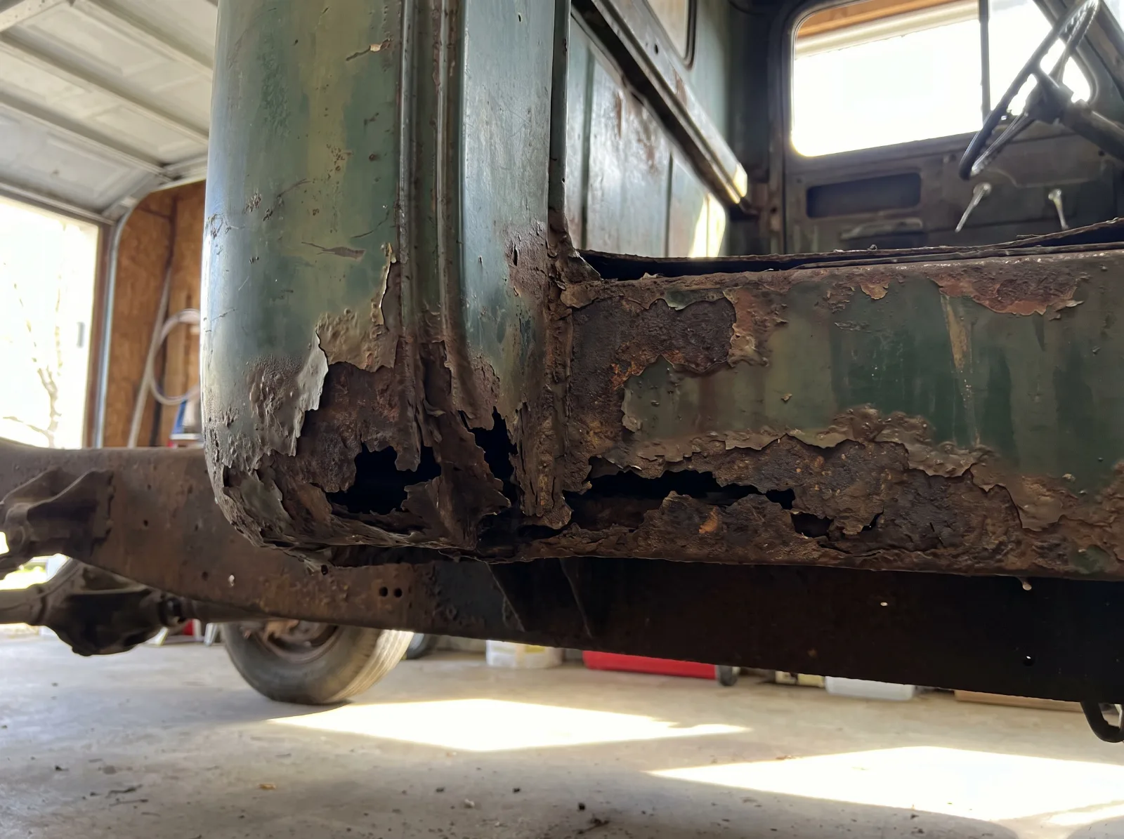 Rusted lower cab corner and floor of an Advance Design truck before repair