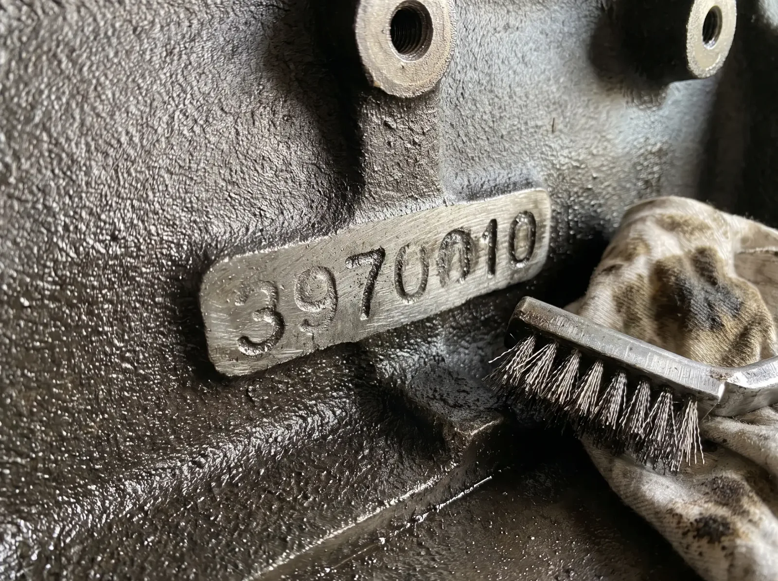 Raised casting number on the side of a vintage cast iron engine block, partly cleaned with a wire brush